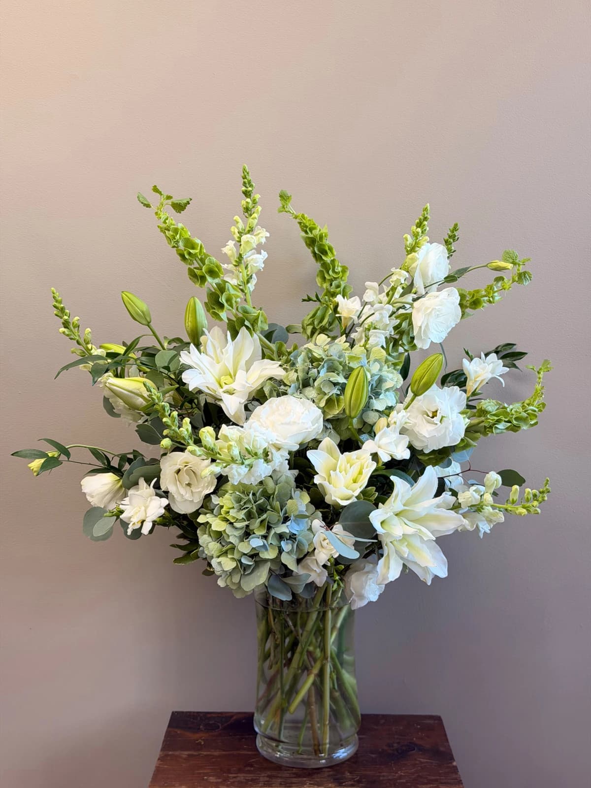 A soft, calming palette of white blooms and delicate blue accents, gathered in an airy, garden-style design. Tall and full, this arrangement makes a striking statement piece — perfect for elevating any space with quiet elegance.