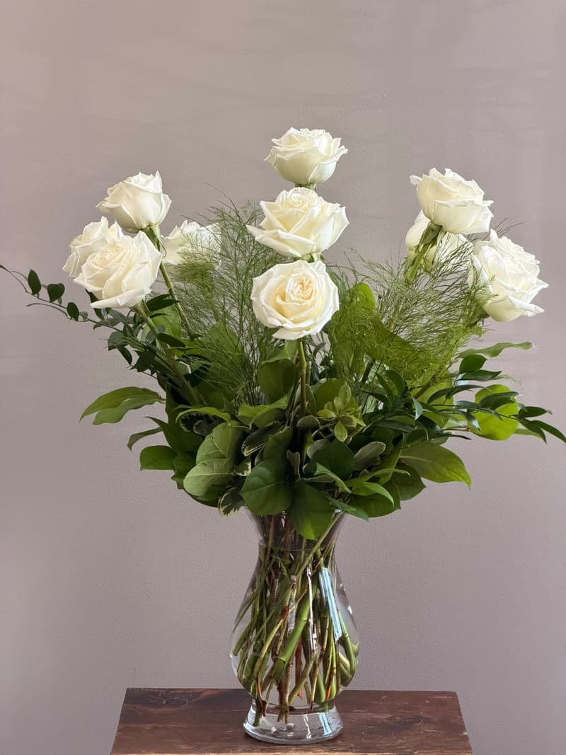 Refined, luminous, and quietly unforgettable. Twelve premium long-stemmed white roses, each selected by hand for its flawless ivory petals and perfectly formed bloom, are composed by our lead designer into an arrangement of effortless elegance. Accented with lush, garden-inspired greenery and finished with our signature wrap or a hand-chosen vase, this is a gift that speaks with grace: of devotion, of new beginnings, of remembrance, of love that needs no explanation. Designed and hand-delivered by The Concord Flower Shop.