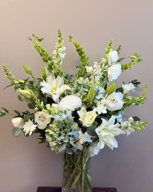White lilies, lisianthus and hydrangea with snapdragons in a glass vase.